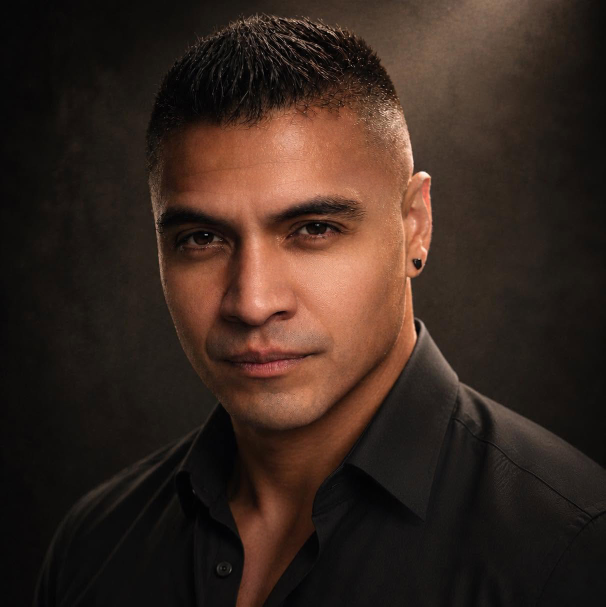 A black-and-white portrait of Luis holding a camera.